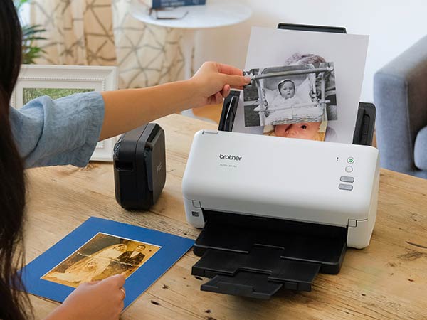 Woman loading various new and antique family photos into scanner
