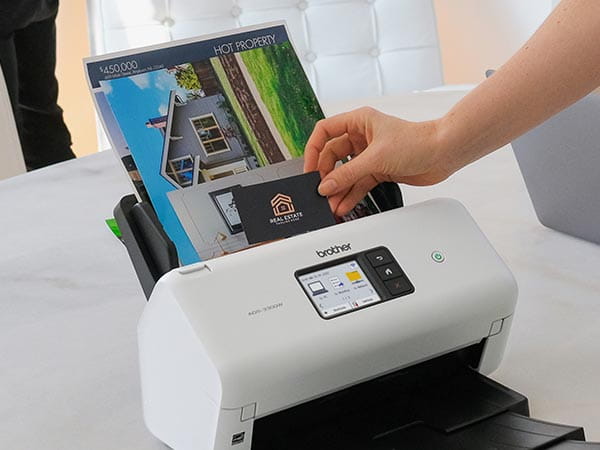 Person placing business cards, postcards, flyers, and letter-size documents together in scanner's automatic document feed
