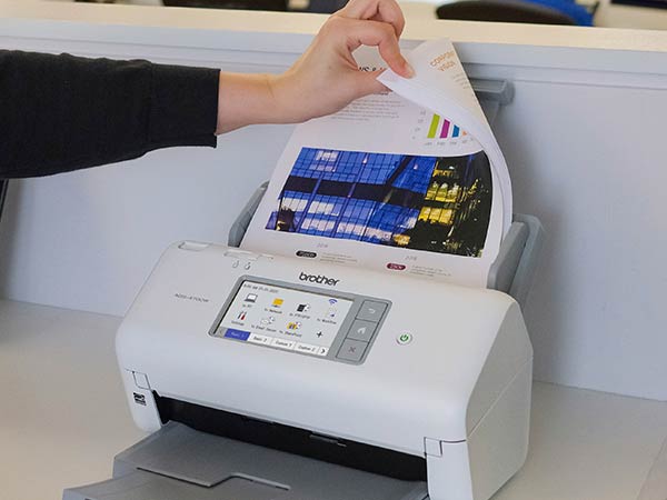 Woman in office placing full color double-sided document into scanner's auto document feed
