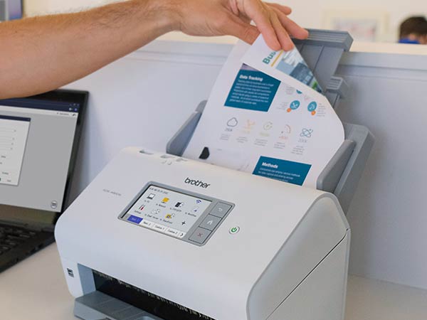 Man in office placing full color double-sided document into scanner's auto document feed