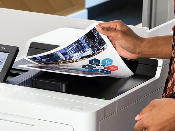 Woman removing multipage color business report from printer's output tray