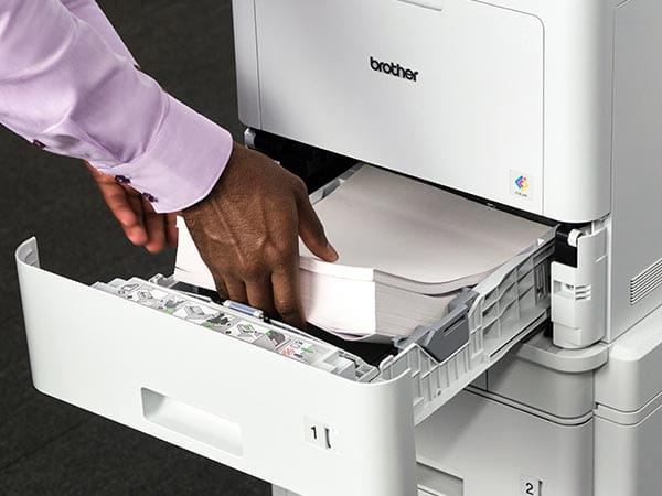Man adding ream of paper to printer's paper tray