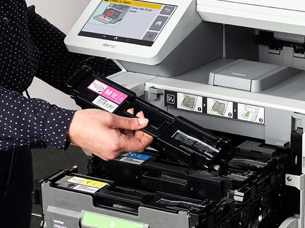 Woman installing new magenta toner cartridge in printer
