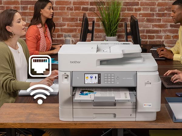 Printer on office conference room counter during meeting, with Ethernet and Wi-Fi icons