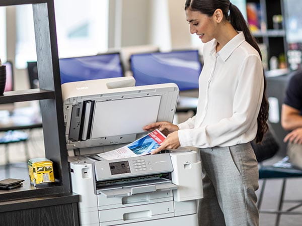 Woman in corporate office placing full color brochure on printer's document scan glass