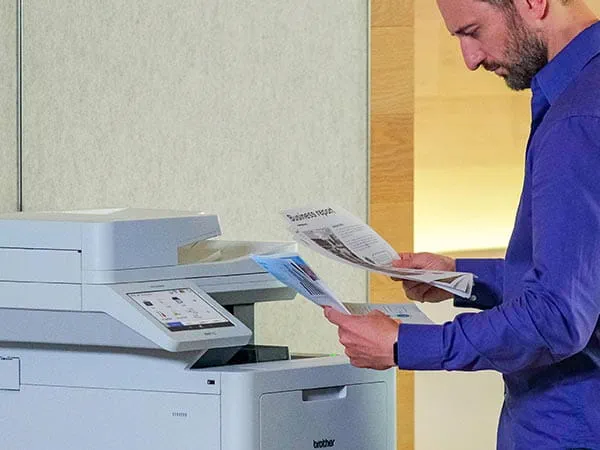 Man removing color business report from printer's output tray
