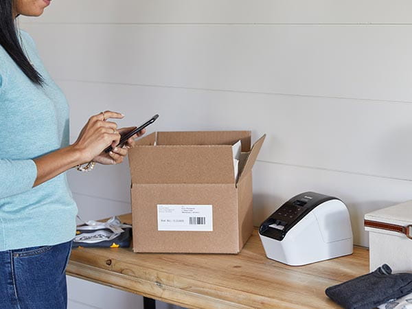 Woman using mobile phone to print shipping labels for small business