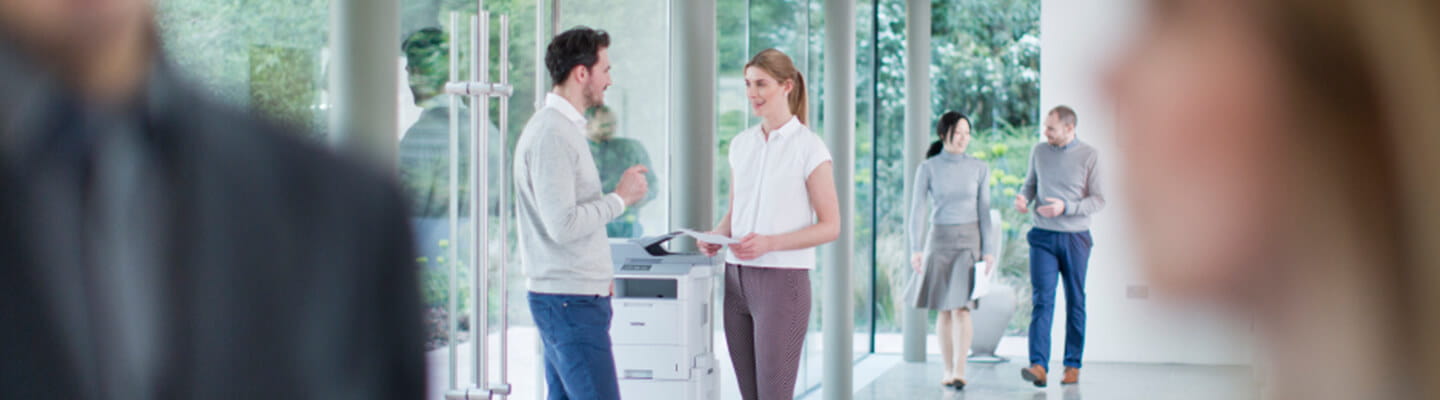 People talking in hallway near a Brother Printer