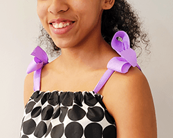woman wearing a polka dot shirt with purple ribbon ties sewn with a Brother sewing machine