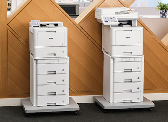 Brother printer and all-in-one in an office near wall featuring the models HL-L947 and MFC-L9670