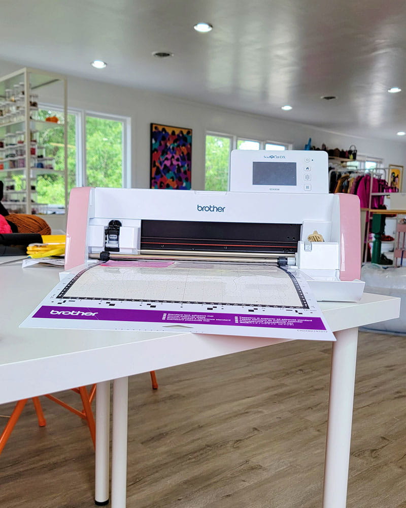 Brother ScanNCut cutting machine on a table with vinyl mat inserted. 