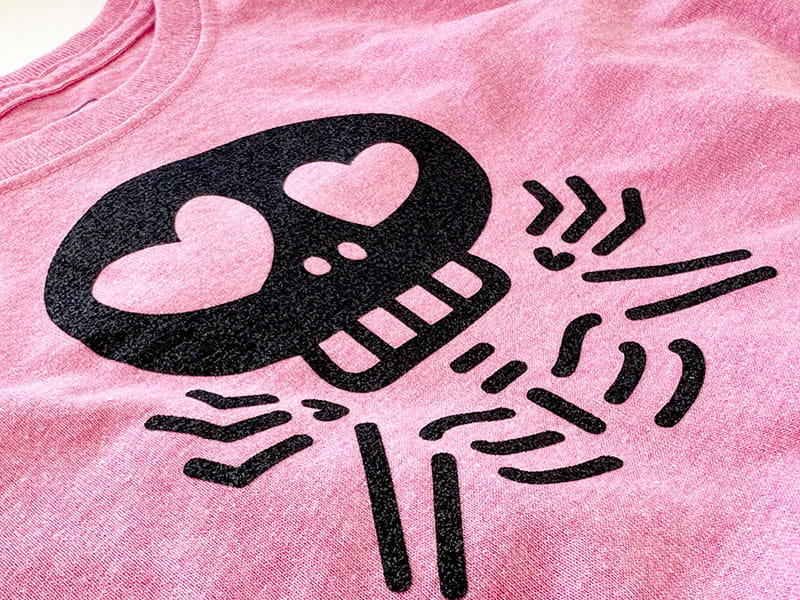 Close up of shrugging skeleton applique on pink shirt. 