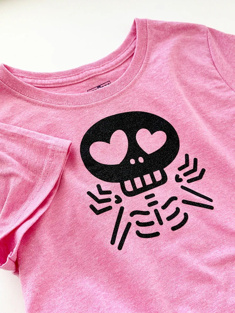 Full view of shrugging skeleton applique on pink shirt. 