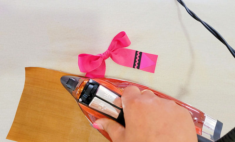 Person ironing left side of pink crayon hair bow
