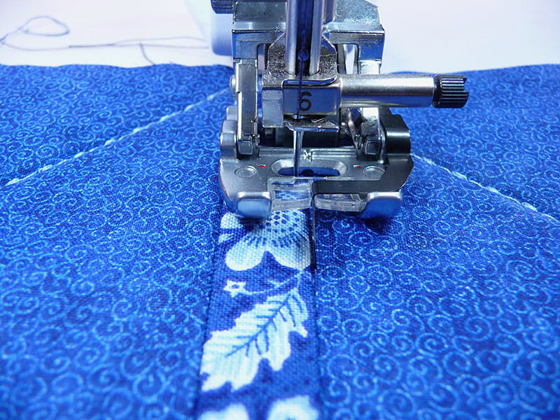 sewing machine sewing the blue fabric on the edge