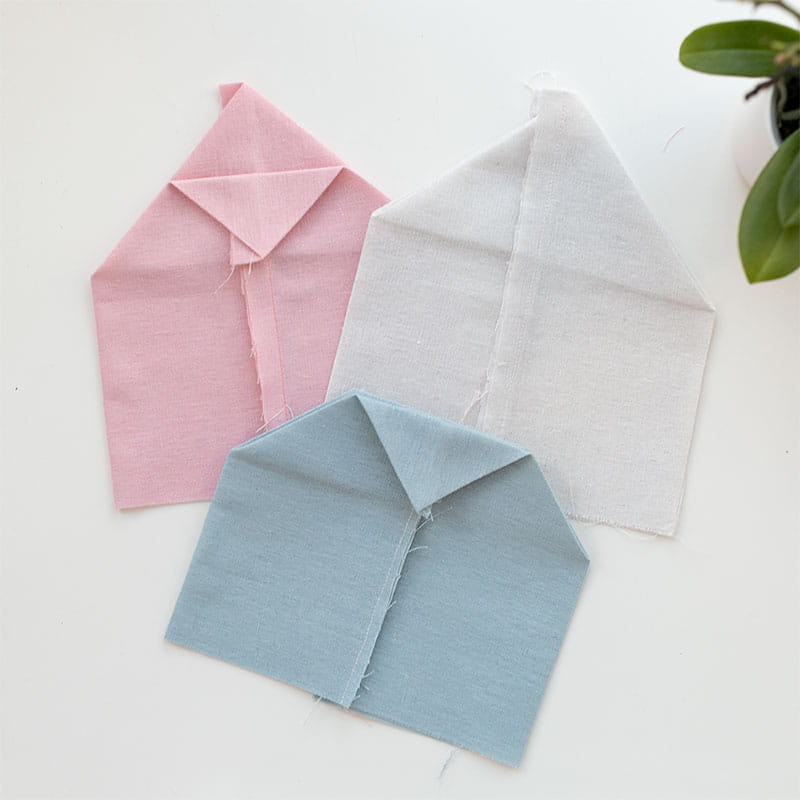 Three folded fabric flower pots in pink, white and blue