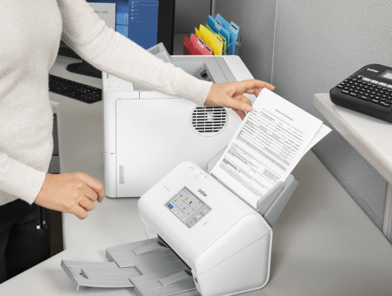 Brother Printer in action with a person holding the paper