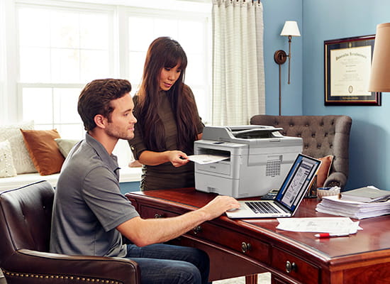 Man and Women working in a home office with a Brother MFC-L2759DW printer