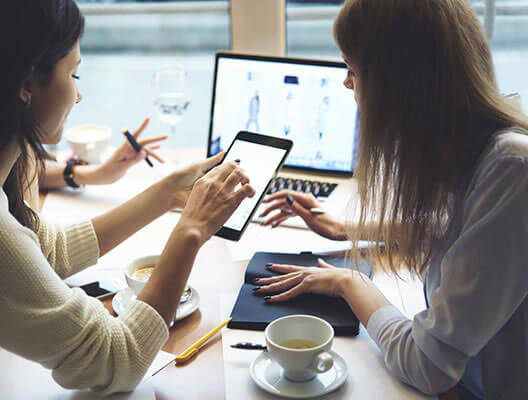Two women working with tablets and a laptop