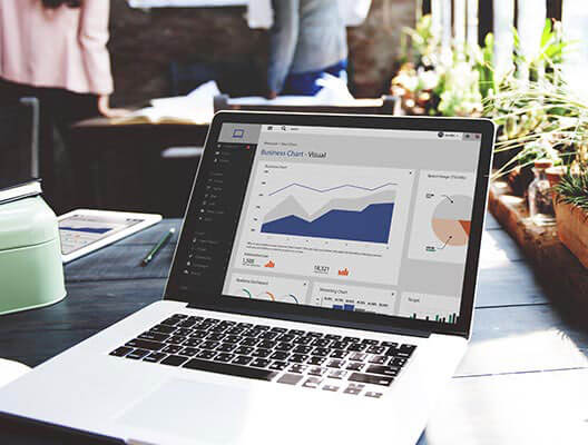 Laptop open on desk with charts and graphs displayed