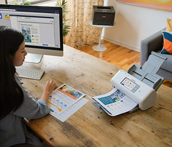 Woman at table with papers going through a Brother scanner