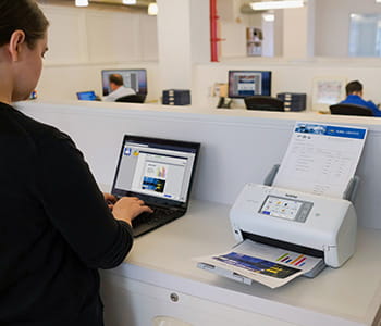 Man using a laptop with an ADS4700W scanner adjacent