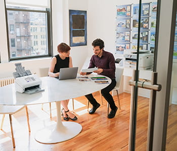 Coworkers in an office examining documents with ADS4900W on table