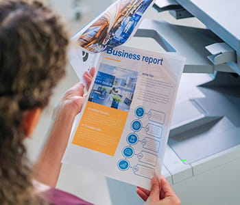 Person reviewing document with HL-L9470CDN Brother printer in the background