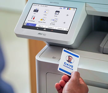 Person scanning badge on MFC-EX670W all-in-one for secure document printing.