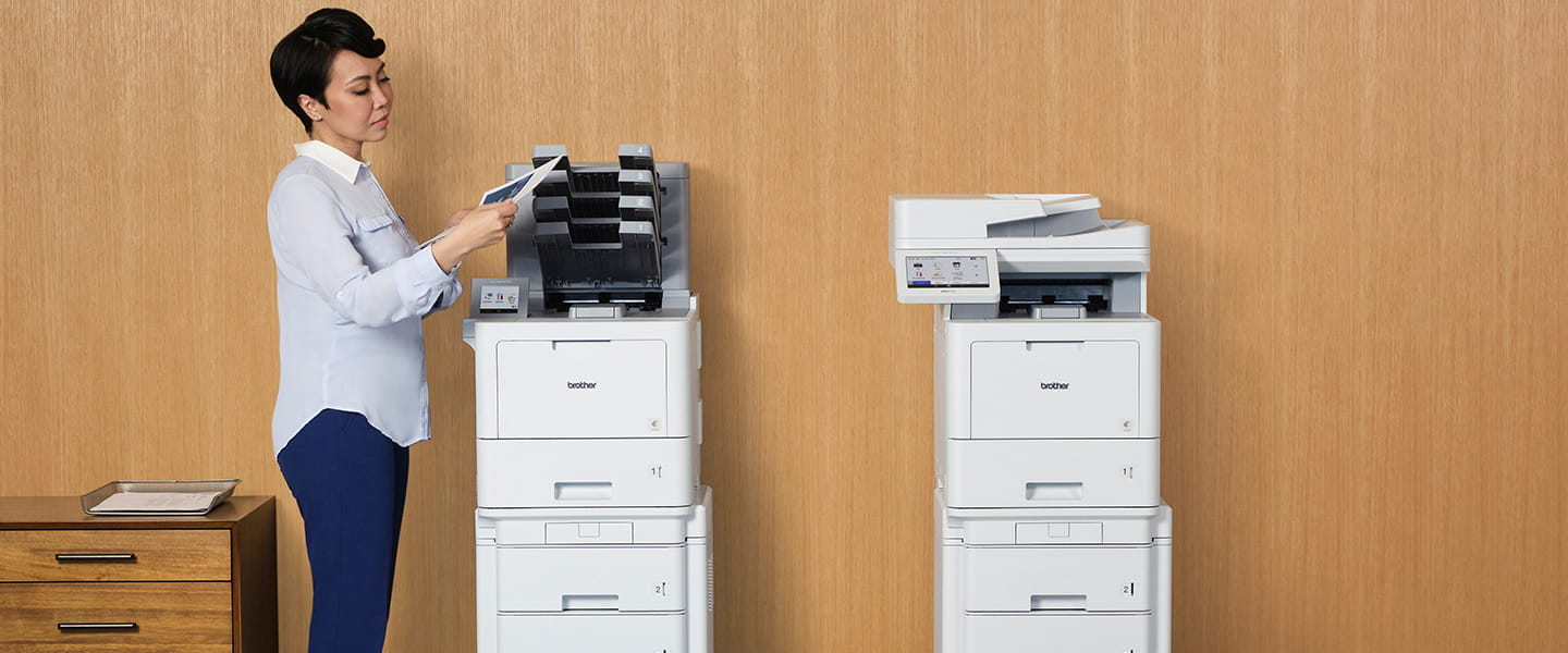 Woman retrieving document from laser printer. HL-L9470 and MFC-L9670 business laser printers in an office space.