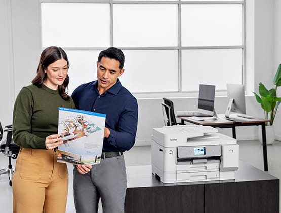 Man and woman reviewing document from a Brother Printer in an office.