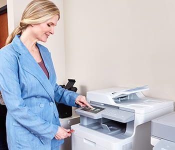 Woman using a Brother workhorse multi-function printer in a small office setting. 