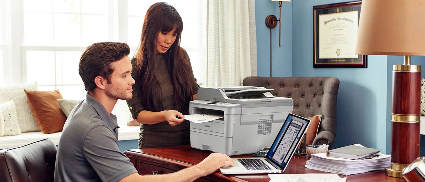 Man and woman in home office printing on Brother MFC-L2759DW all-in-one printer