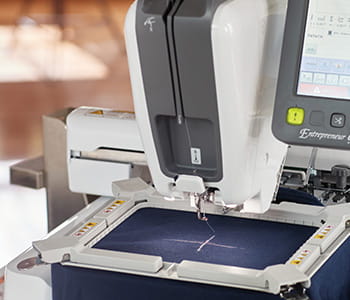 PR1X embroidery machine 2-point positioning laser feature creating a + on navy fabric.