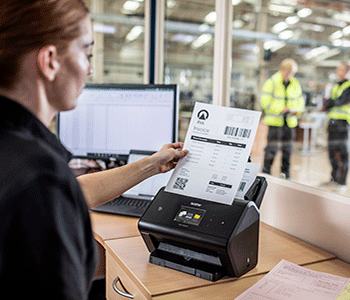 Woman loading document into scanner overlooking warehouse floor