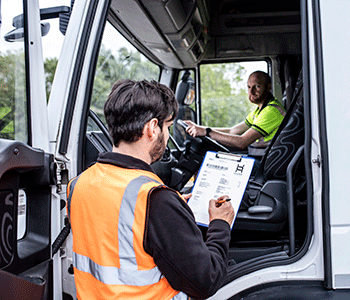 Man with clipboard talking to truck driver