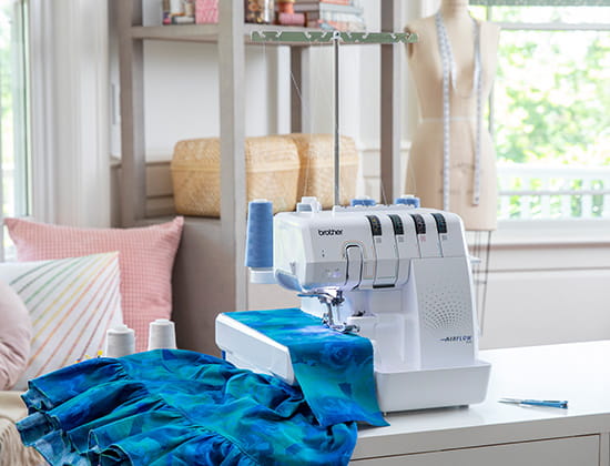 Brother AIRFLOW300 air serger machine on a desk with teal fabric on arm. 