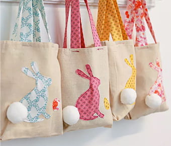 4 totes with Easter bunnies in various spring colors hanging up. 