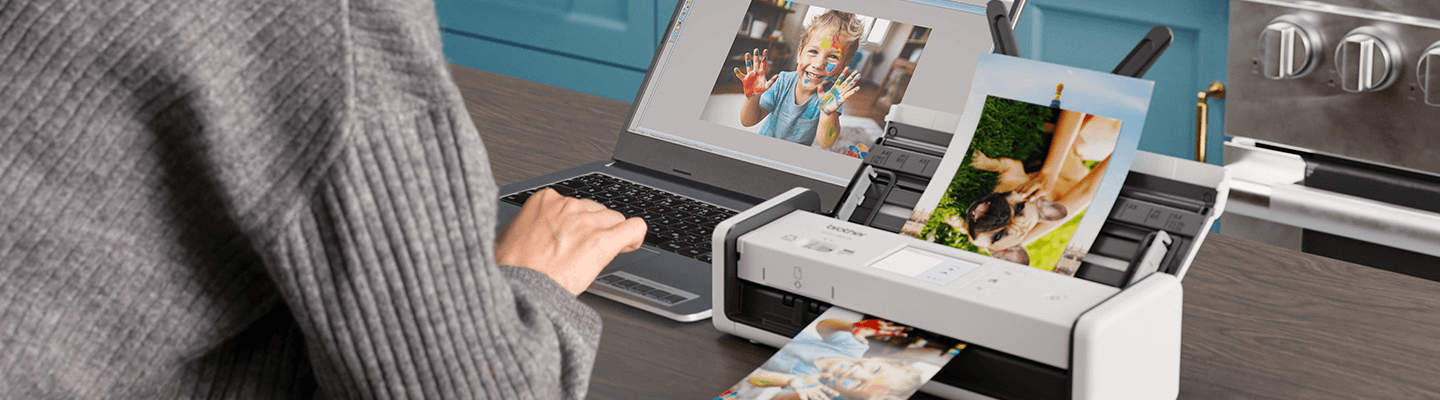 Person using a Brother desktop scanner to upload pictures to computer.