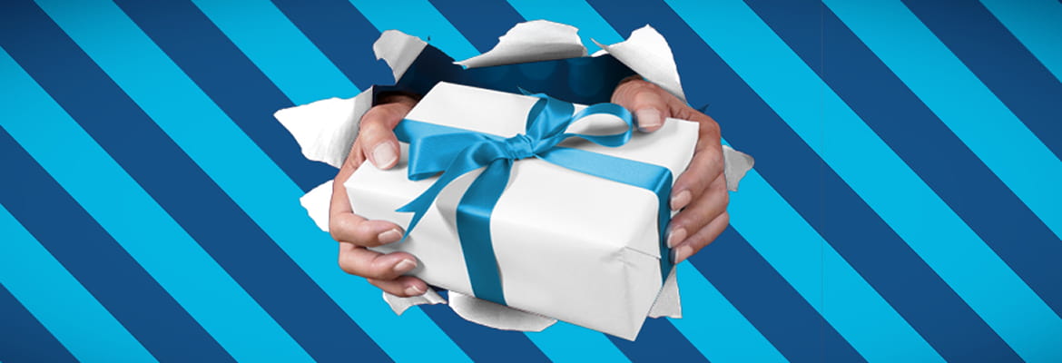 Hands holding a white wrapped present with blue ribbon on a blue striped background