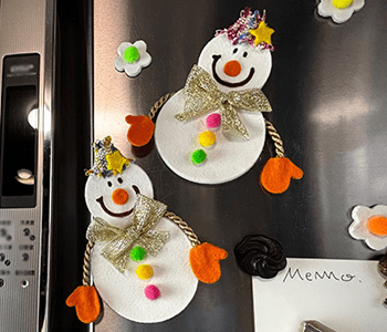 Two paper snowmen on a refrigerator.