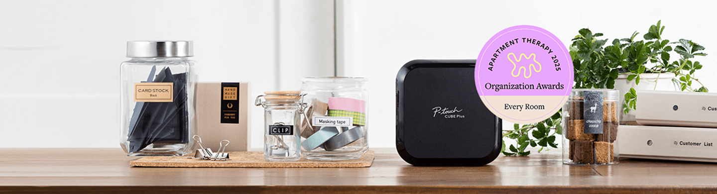 P-touch Cube plus on a counter with labeled jars and office supplies. 