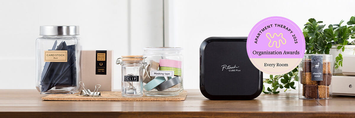 P-touch Cube plus on a counter with labeled jars and office supplies. 