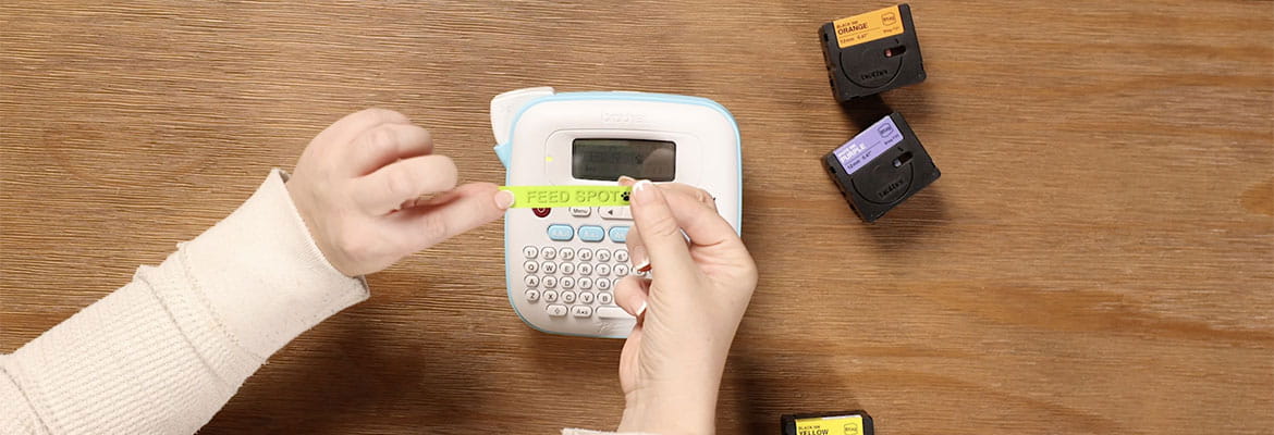 Person holding a yellow Btag label tape with "Feed Spot" text