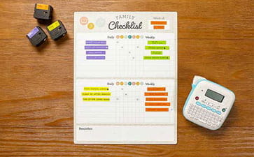 Chore chart on table next to Ptouch Btag label maker and label tape cartridges