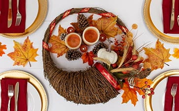 Cornucopia centerpiece with Ptouch Embellish ribbon and orange leaves and pinecones on a table.