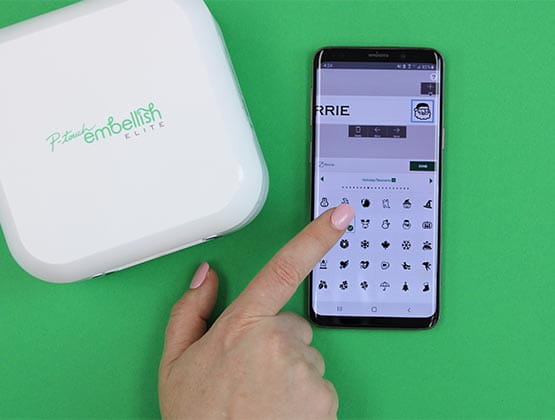 Person creating label on phone next to Ptouch Embellish. 