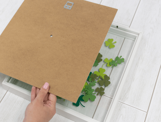 Step 6: Person adding shamrocks to front of the shadowbox for Ptouch Embellish project.