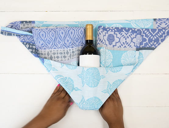 P-touch embellish craft step 2: Person folding tea towel with wine bottle in a pocket