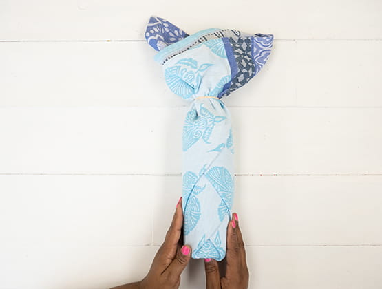 P-touch embellish craft step 4: person holding wrapped wine bottle with a rubber band closing top